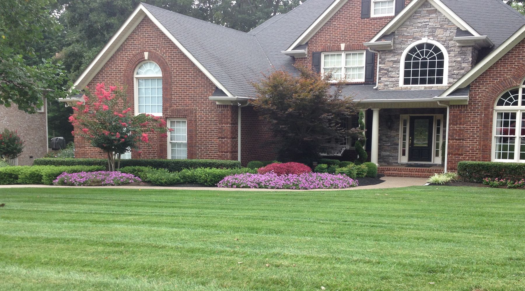 Picture of a brick home with manicured lawn and colorful flowers.