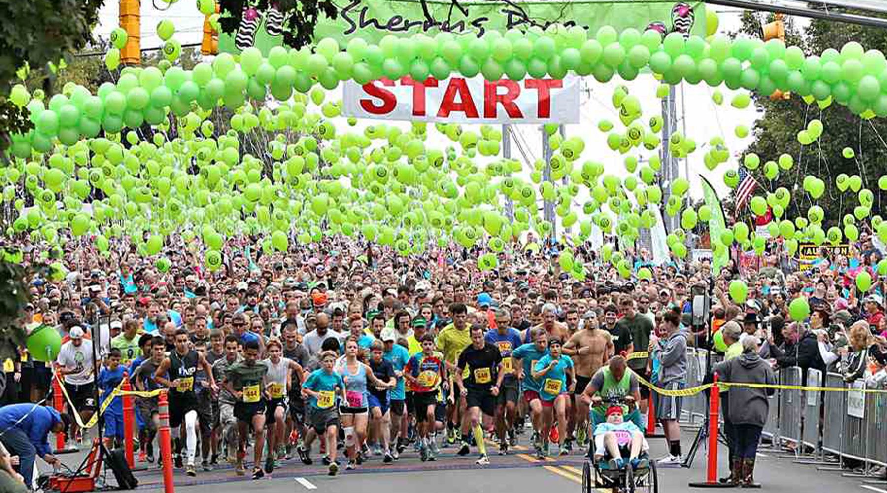 Picture of the starting line of a marathon with lime green balloons surrounding the runners.