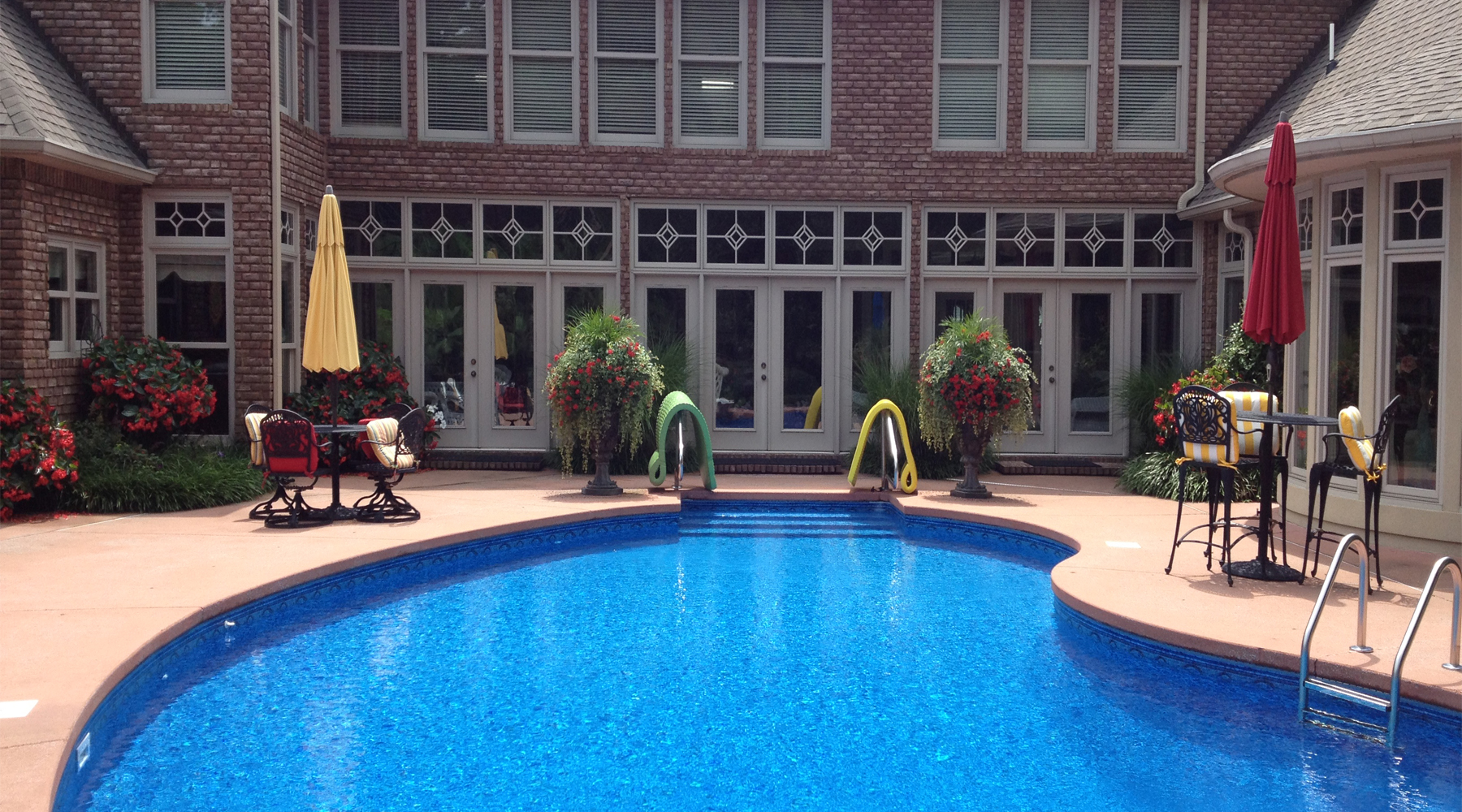 Picture of a swimming pool with a brick home in the background.